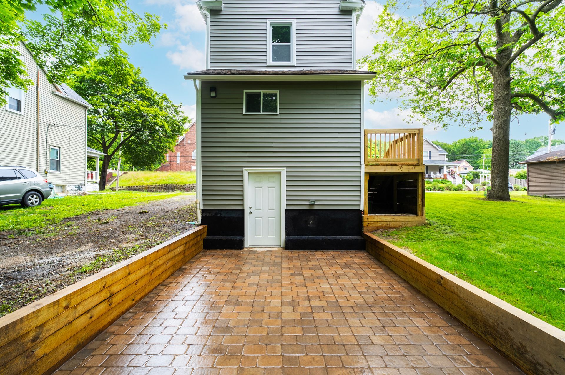 A small house with a brick driveway leading to it.