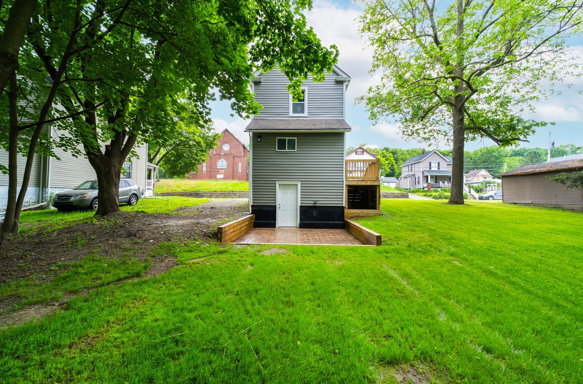 A small house is sitting in the middle of a lush green yard.