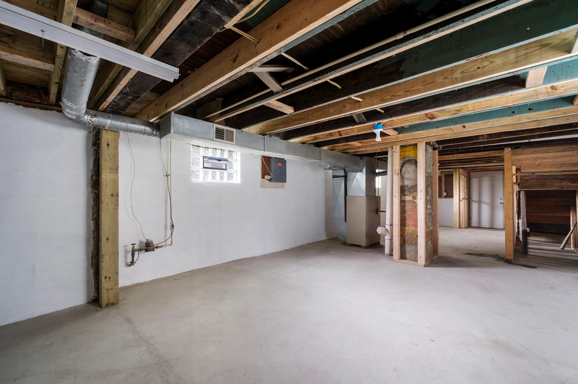 An empty basement with a wooden ceiling and a window.