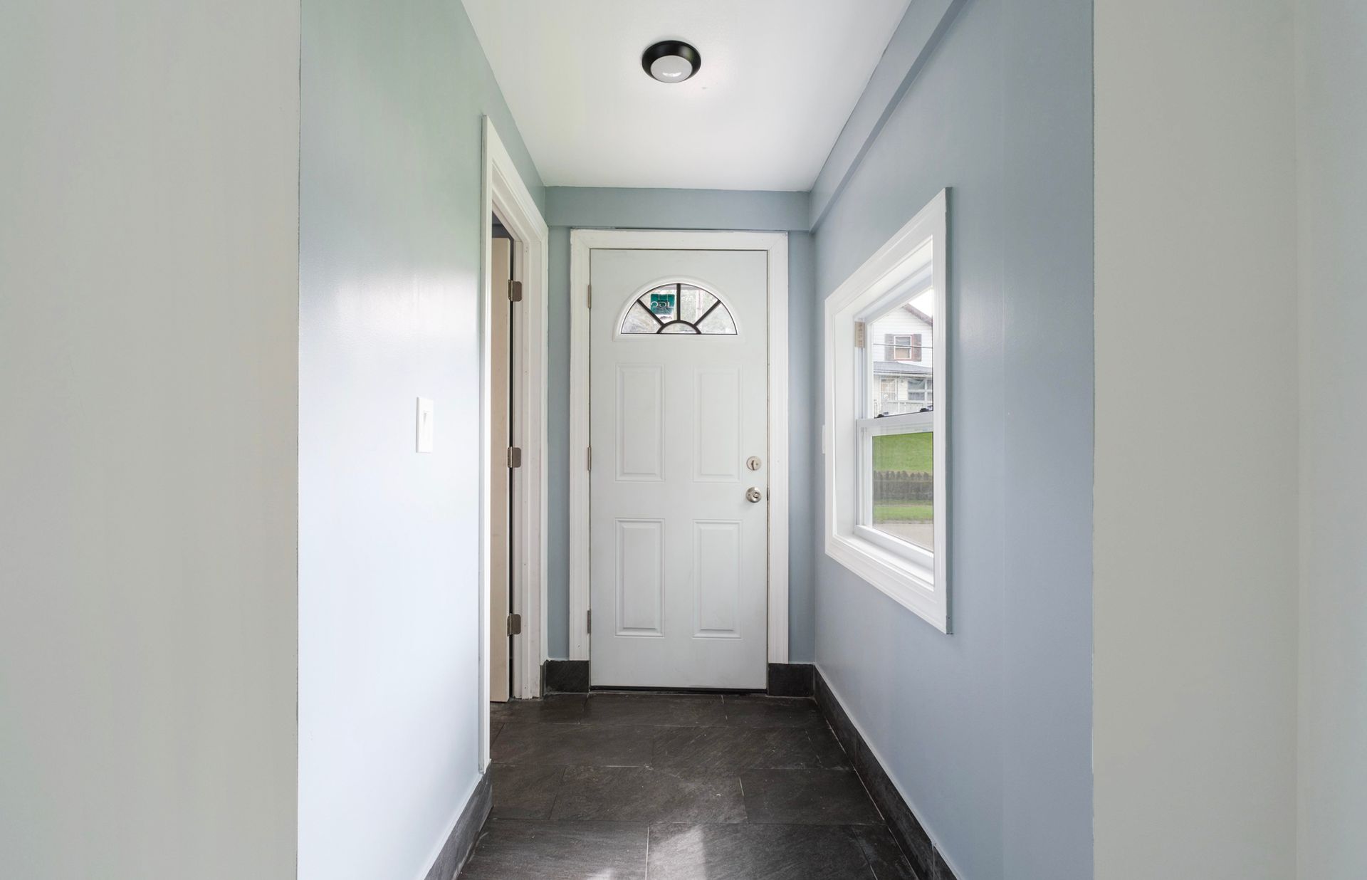 A hallway with a white door and a window.