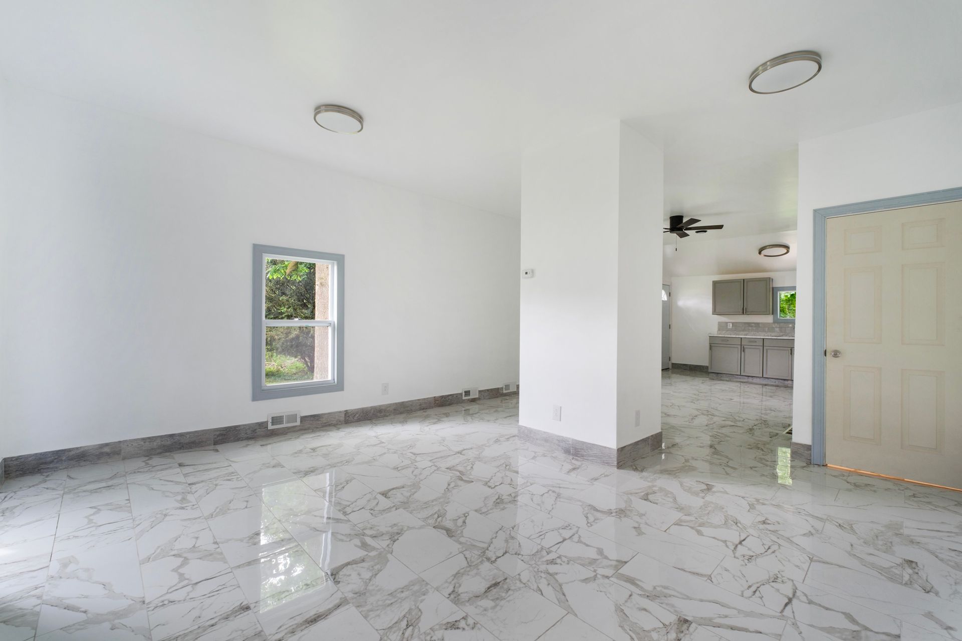 An empty living room with marble floors and a ceiling fan.