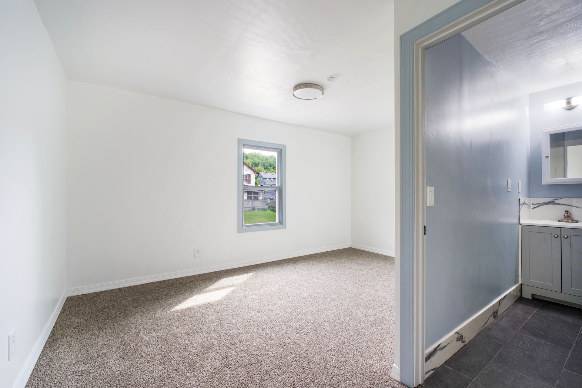 An empty room with a window and a sink in it.