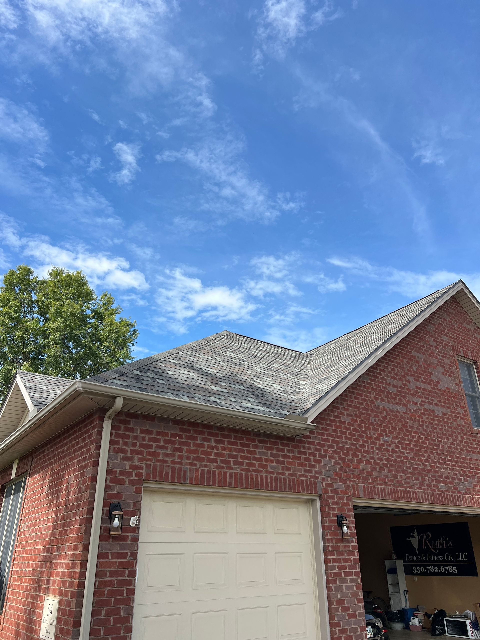 A brick house with a white garage door and a blue sky in the background.