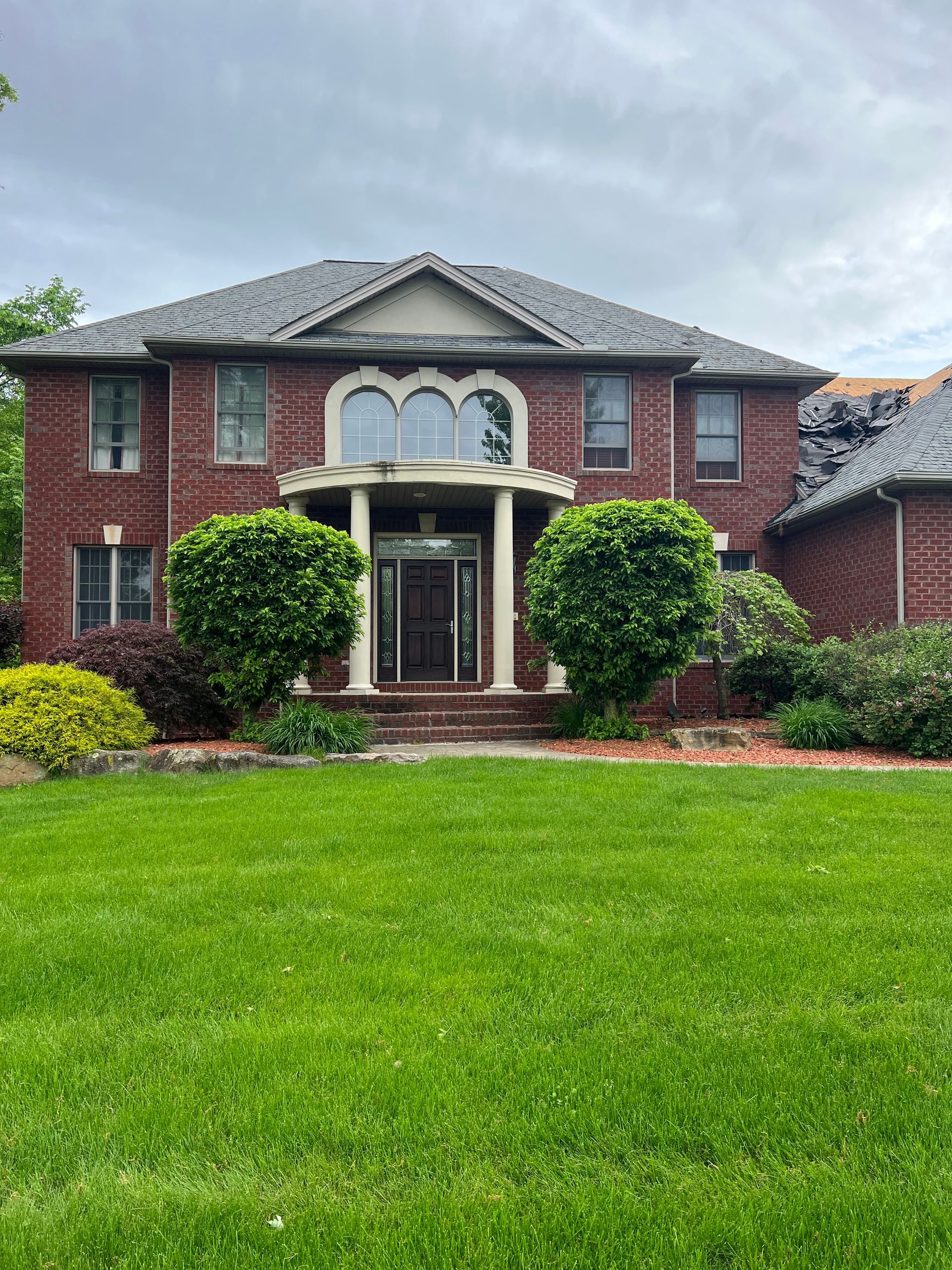 A large brick house with a lush green lawn in front of it.