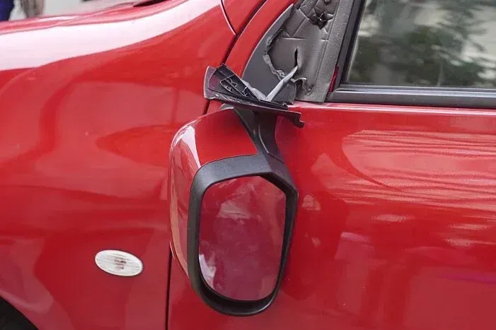 Red car with a broken side mirror.