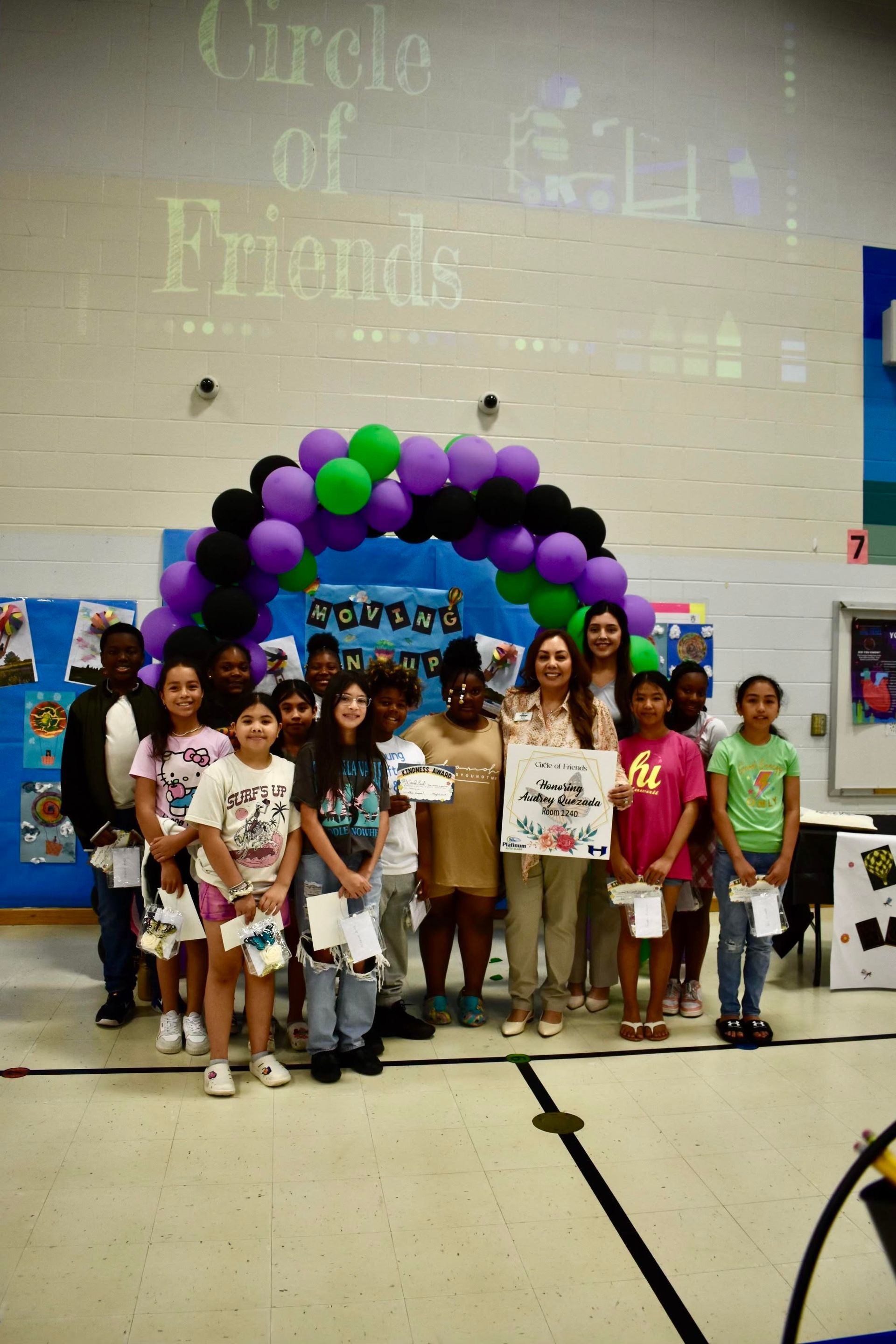 Group of kids and adults pose in front of a balloon arch.