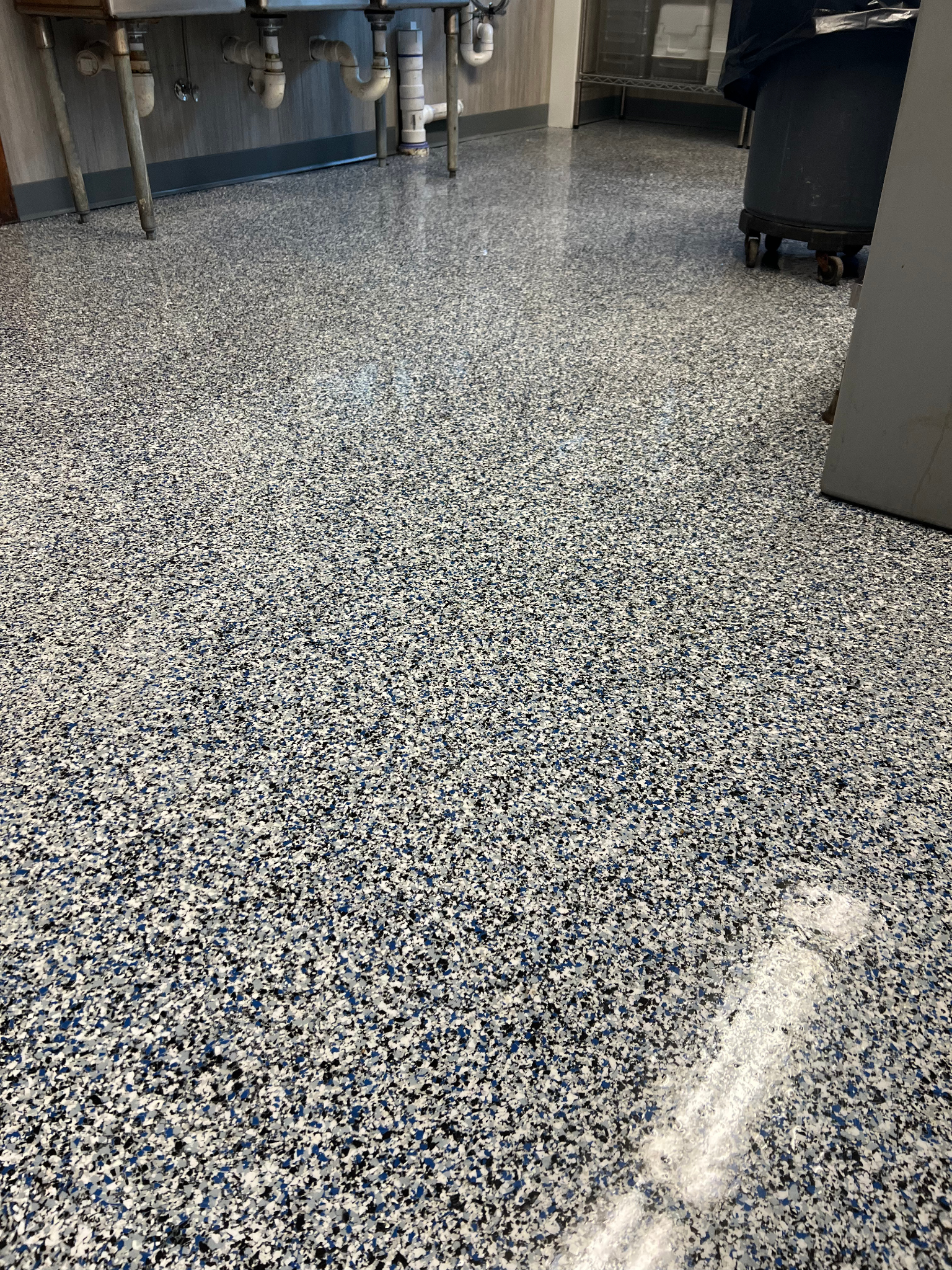 Speckled epoxy floor in a room with tables and equipment along the walls