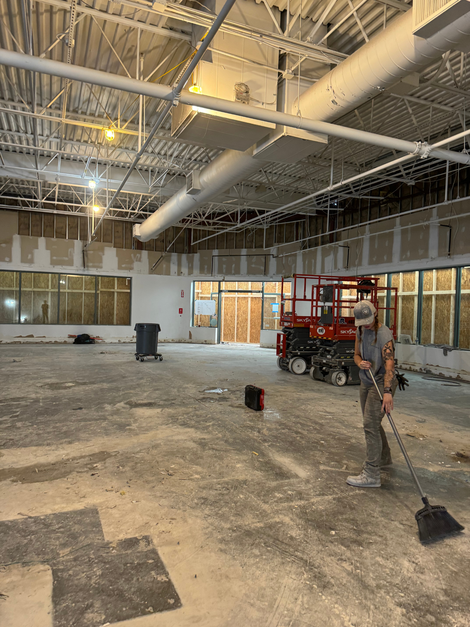 Construction worker standing in a large unfinished building with exposed ceiling and scattered tools