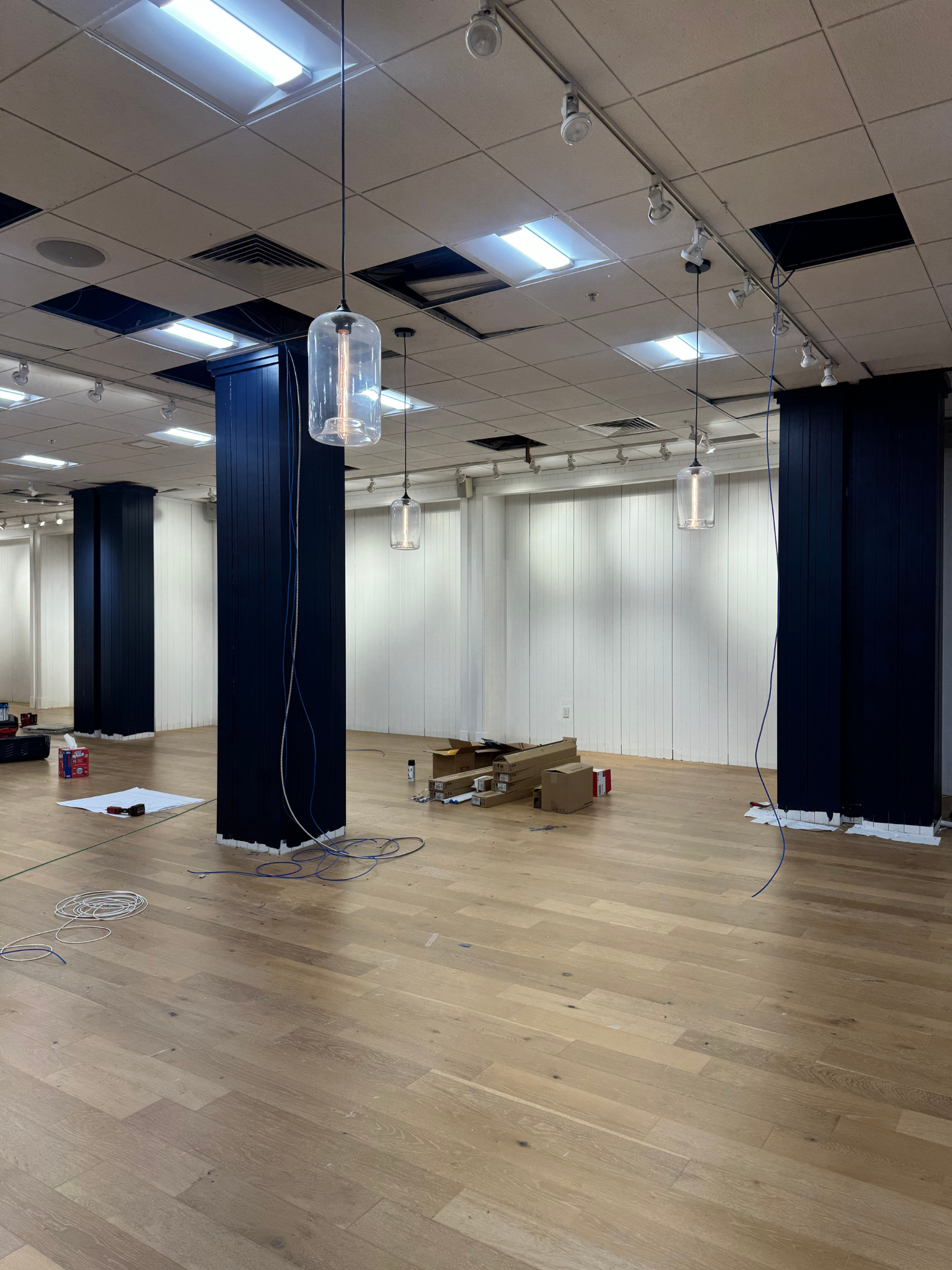 Empty office space with wood floors, white walls, and ceiling lights during renovation