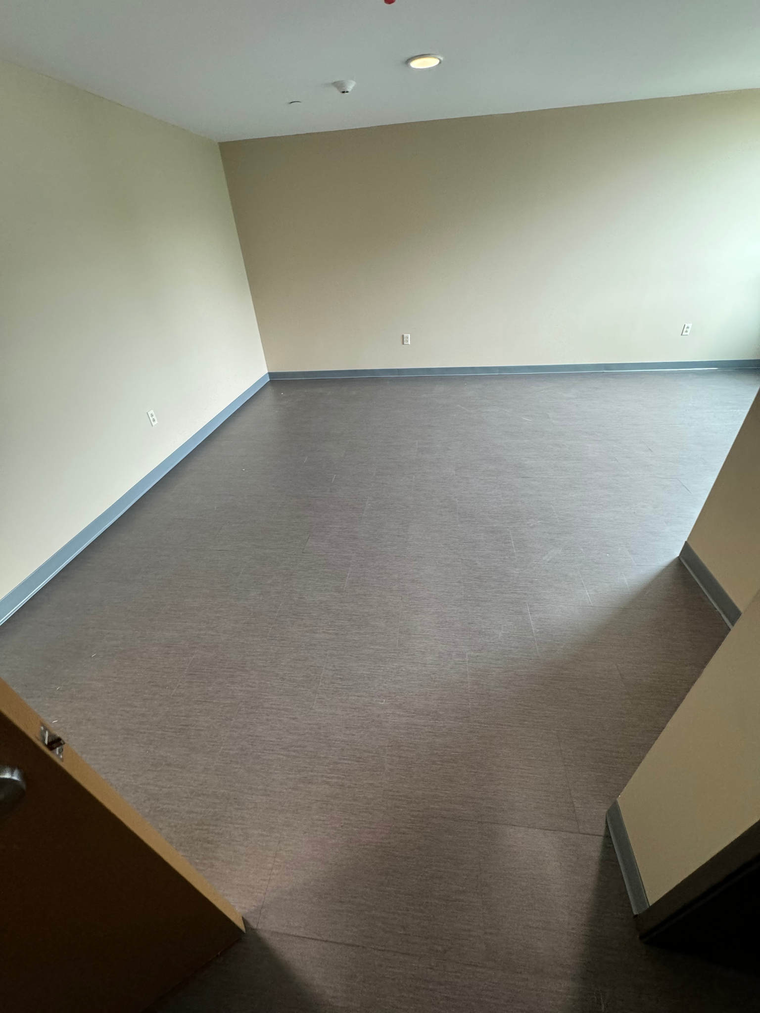 Empty carpeted office room with beige walls and an open door.