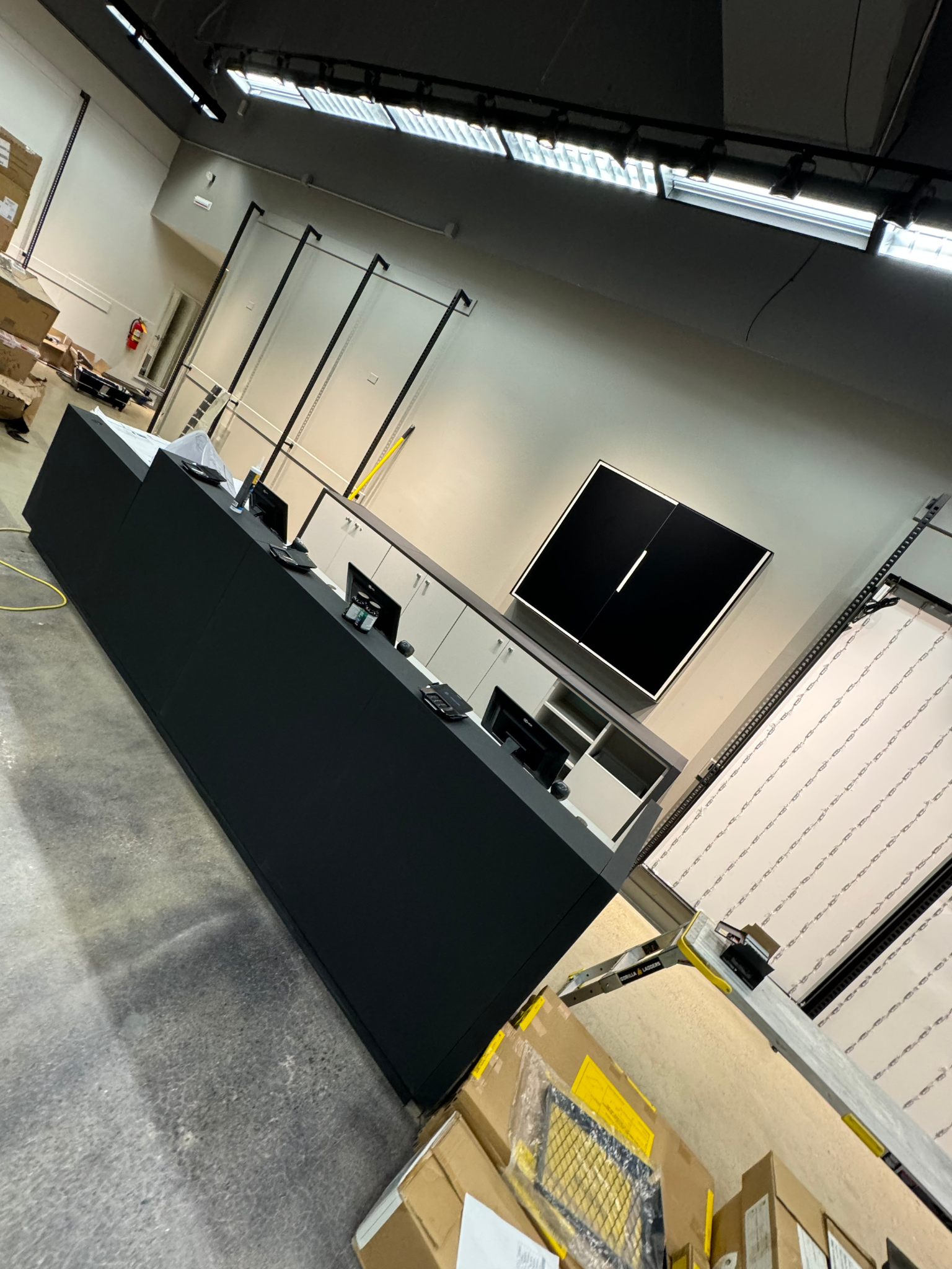 Indoor expo booth with long black counter, mounted displays, and high ceiling lights in a large hall