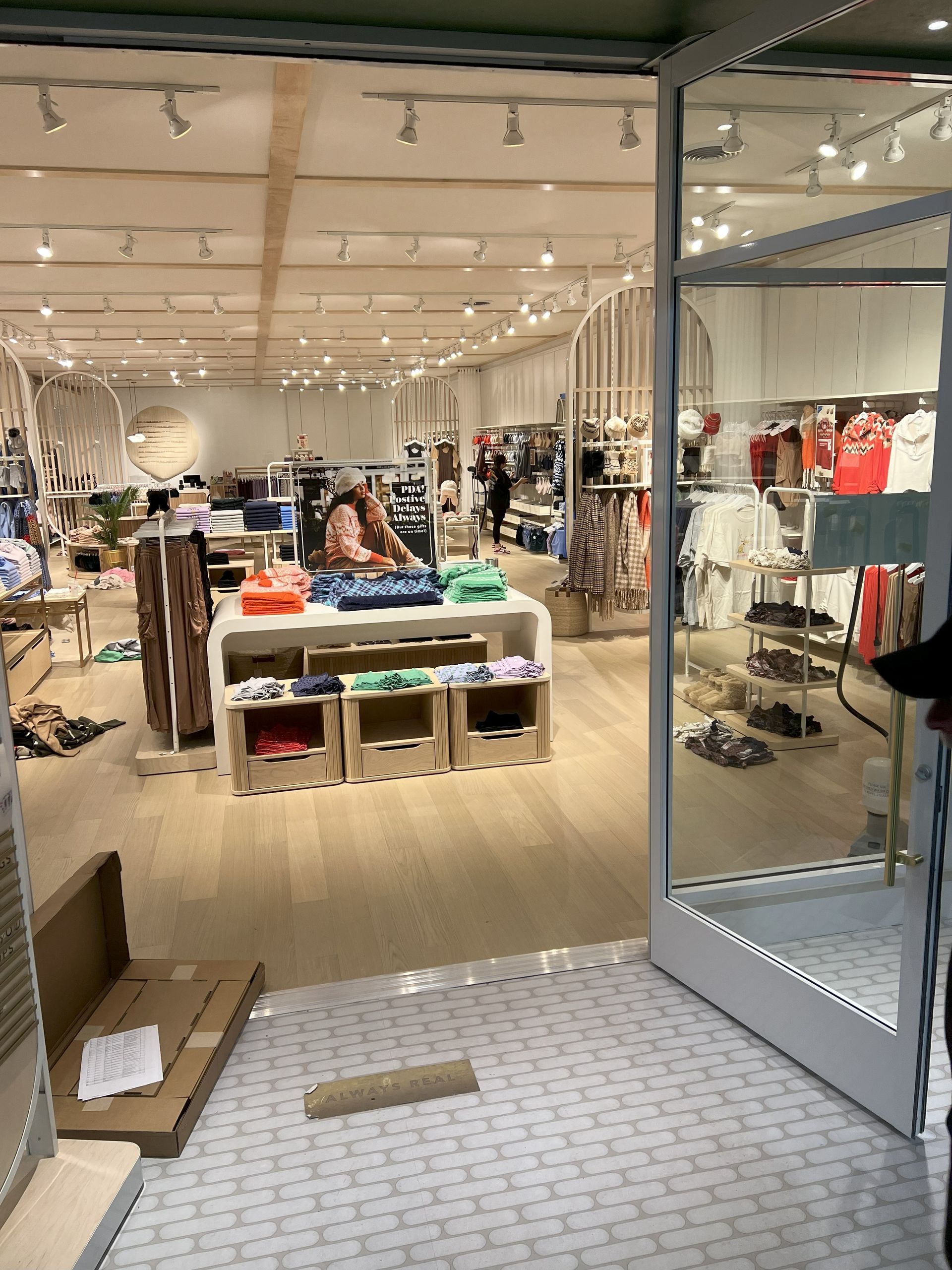 Clothing store interior with racks of clothes and a display table near an open entrance