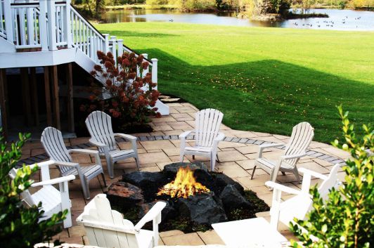 A backyard with a stone wall, chairs, and a swing