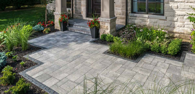 Stone patio with flower beds and a house entrance.