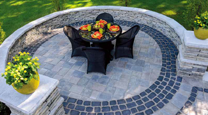 Outdoor dining area with stone patio, round table, and black wicker chairs.