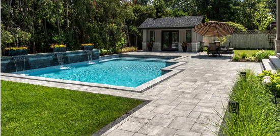 A backyard with a pool, patio, and cabana. Lush green grass and trees surround the area.
