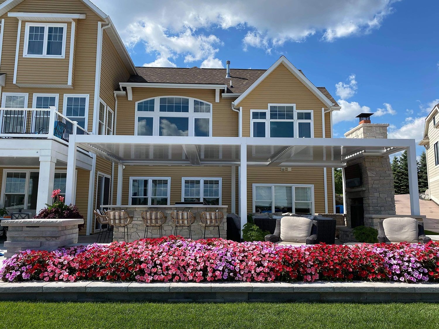 A large house with a pergola and flowers in front of it