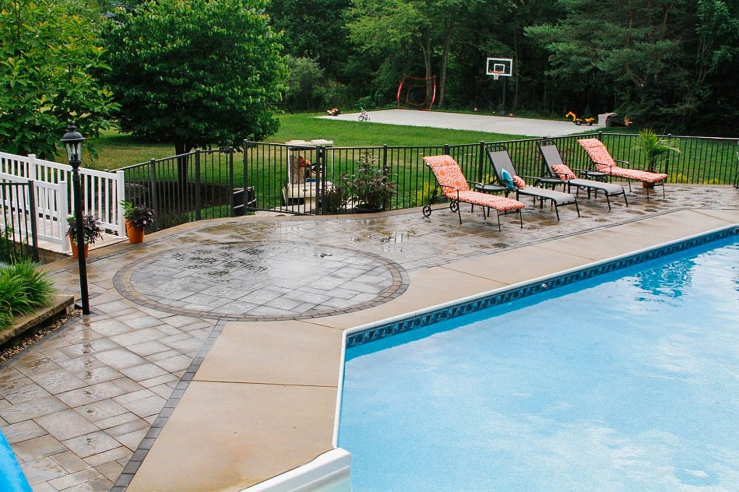 A swimming pool with chairs and a basketball hoop in the background