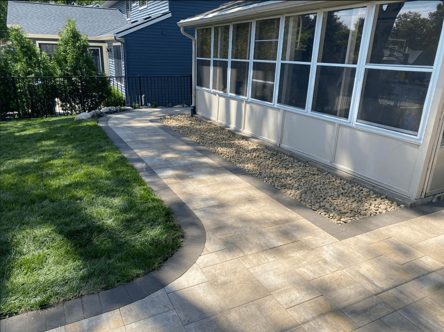 A walkway leading to a house with a screened in porch.