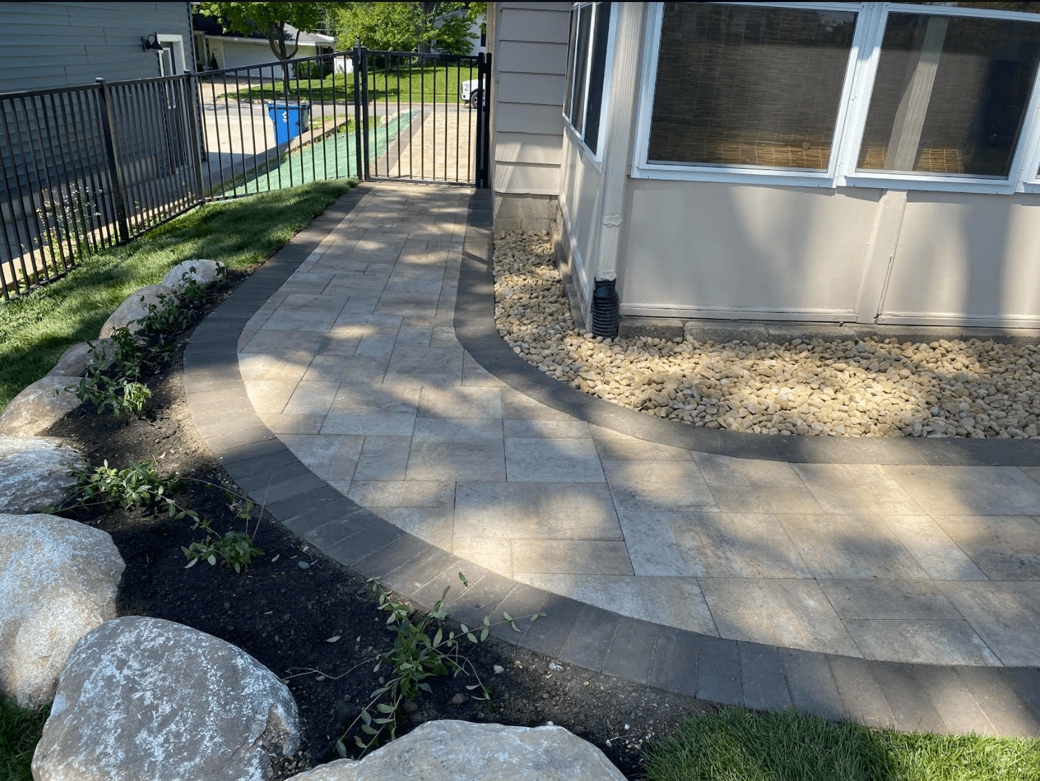 A walkway leading to a house with a screened in porch.