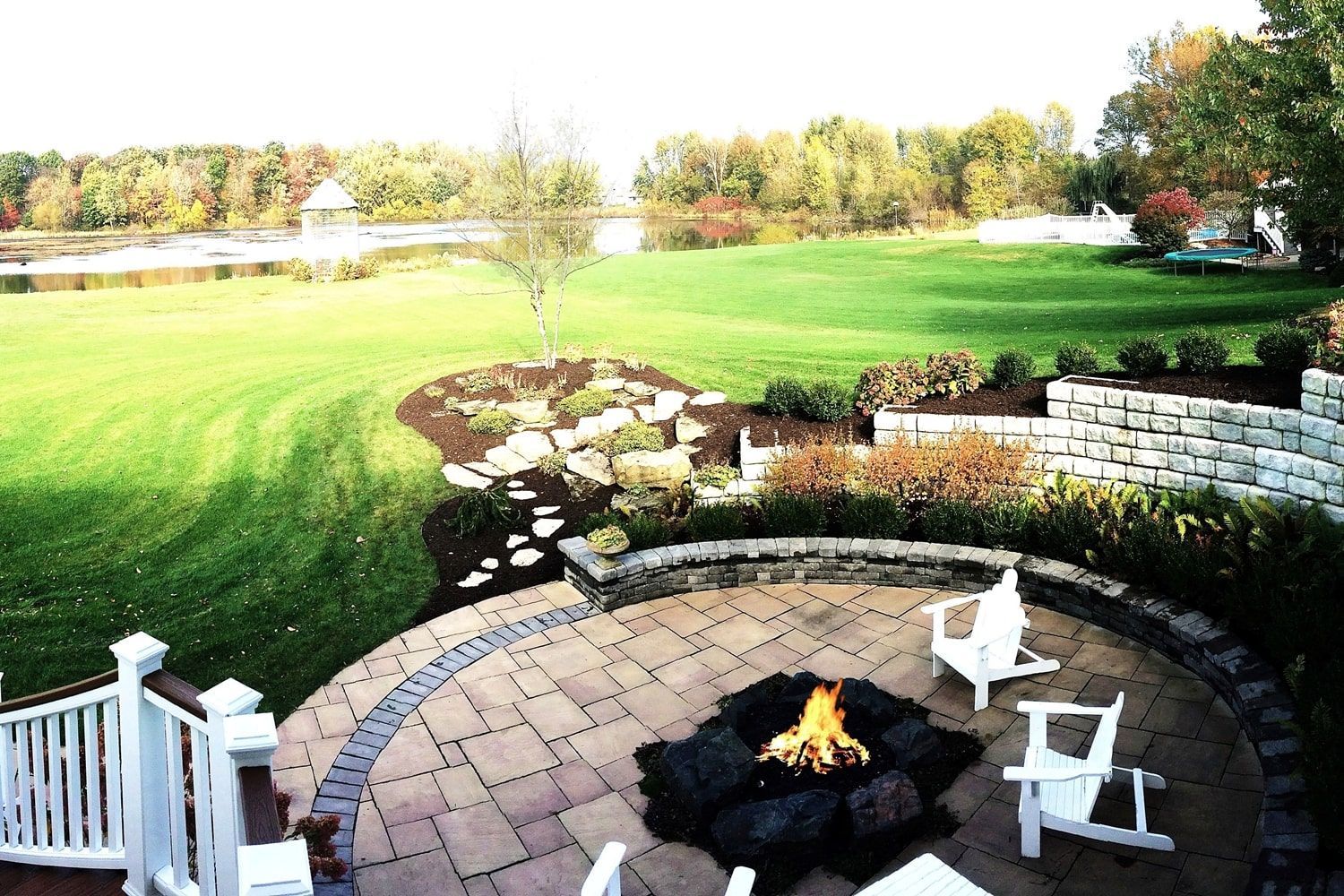 A fire pit in the middle of a patio with chairs around it