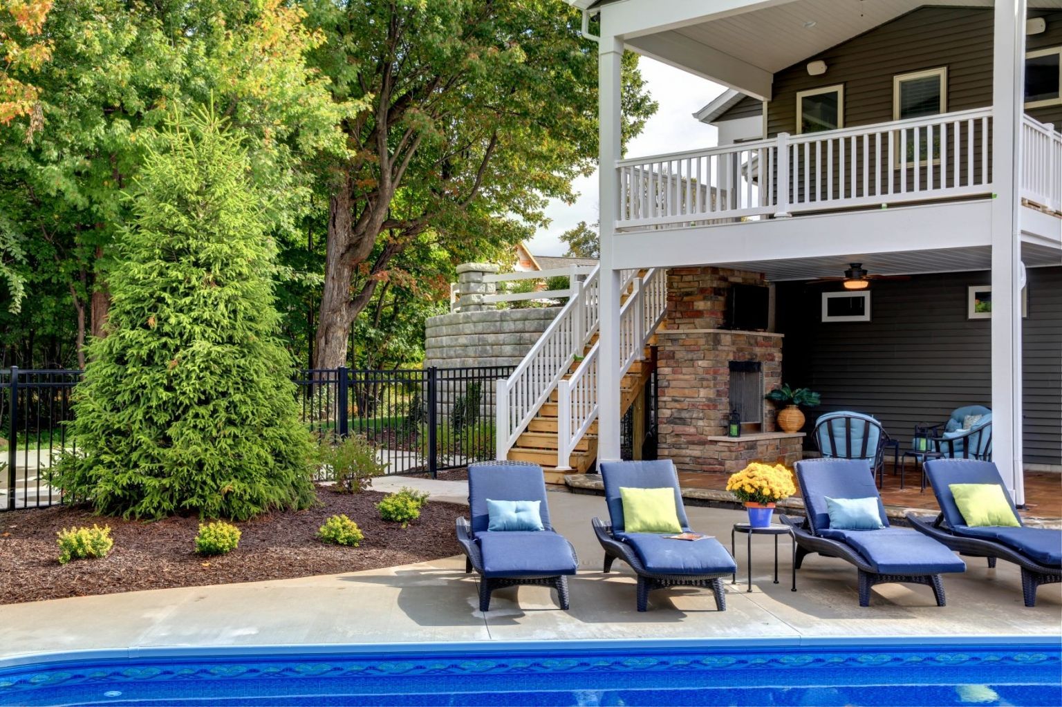 There is a large swimming pool in the backyard of a house.