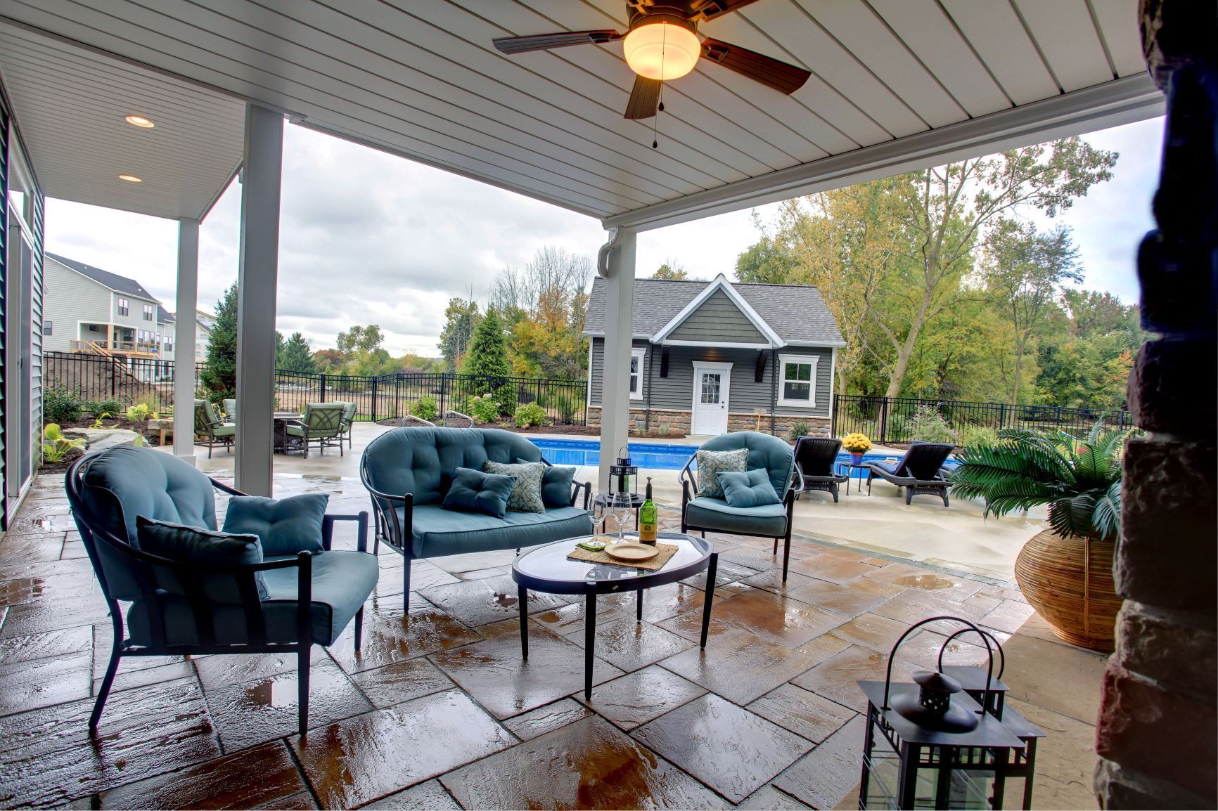 A patio with a couch , chairs , a table and a ceiling fan.