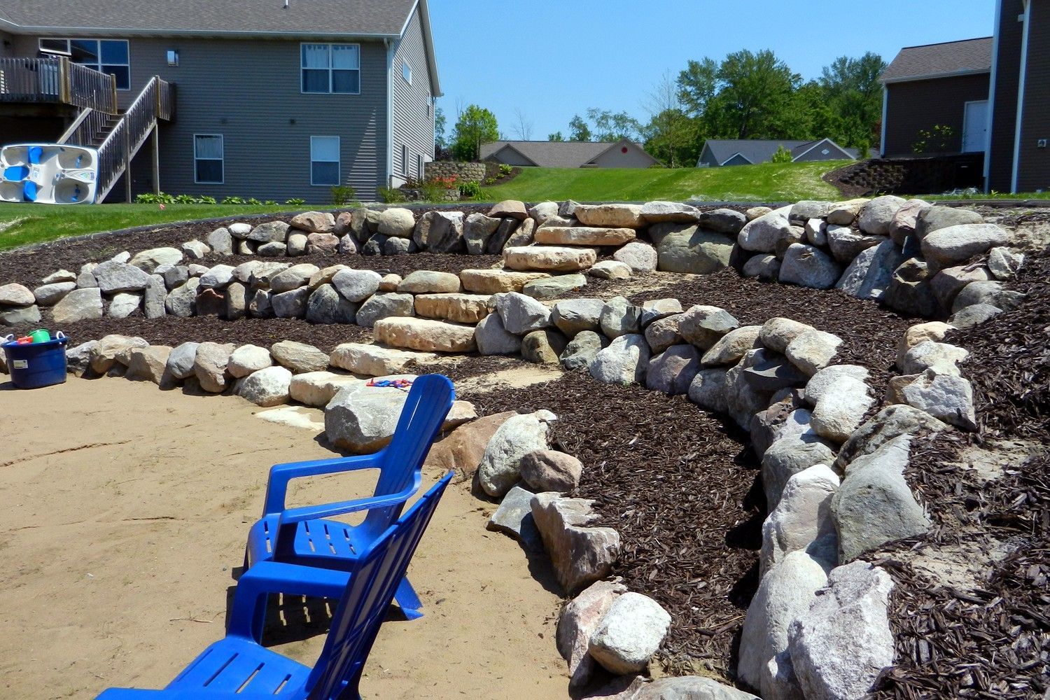 Two blue chairs are sitting in front of a rock wall