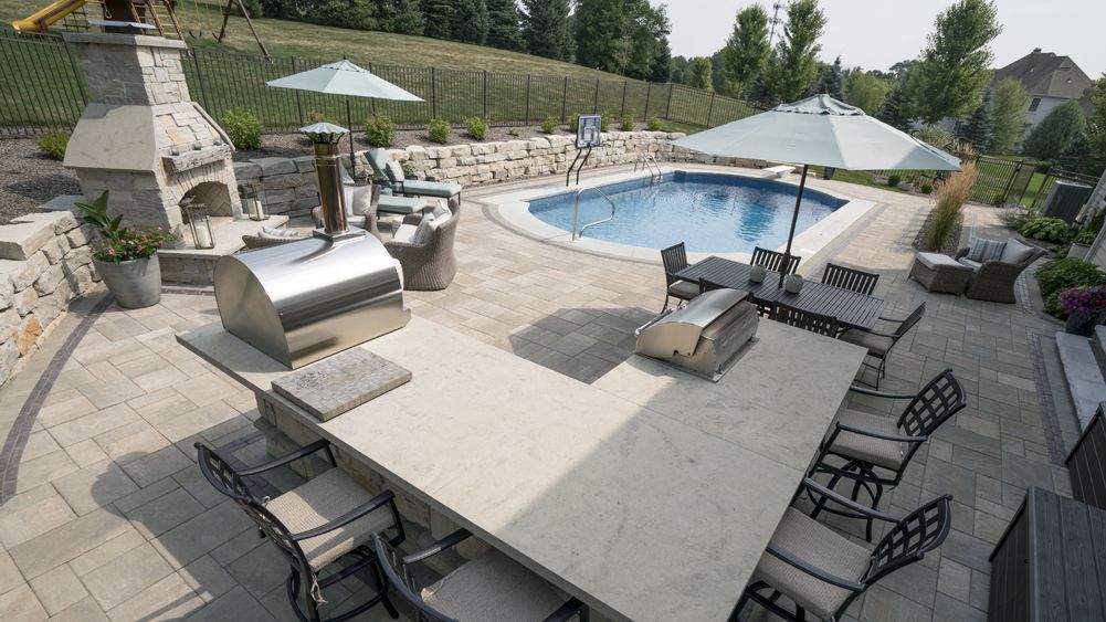 Outdoor patio with a pool, kitchen, fireplace, and seating areas.