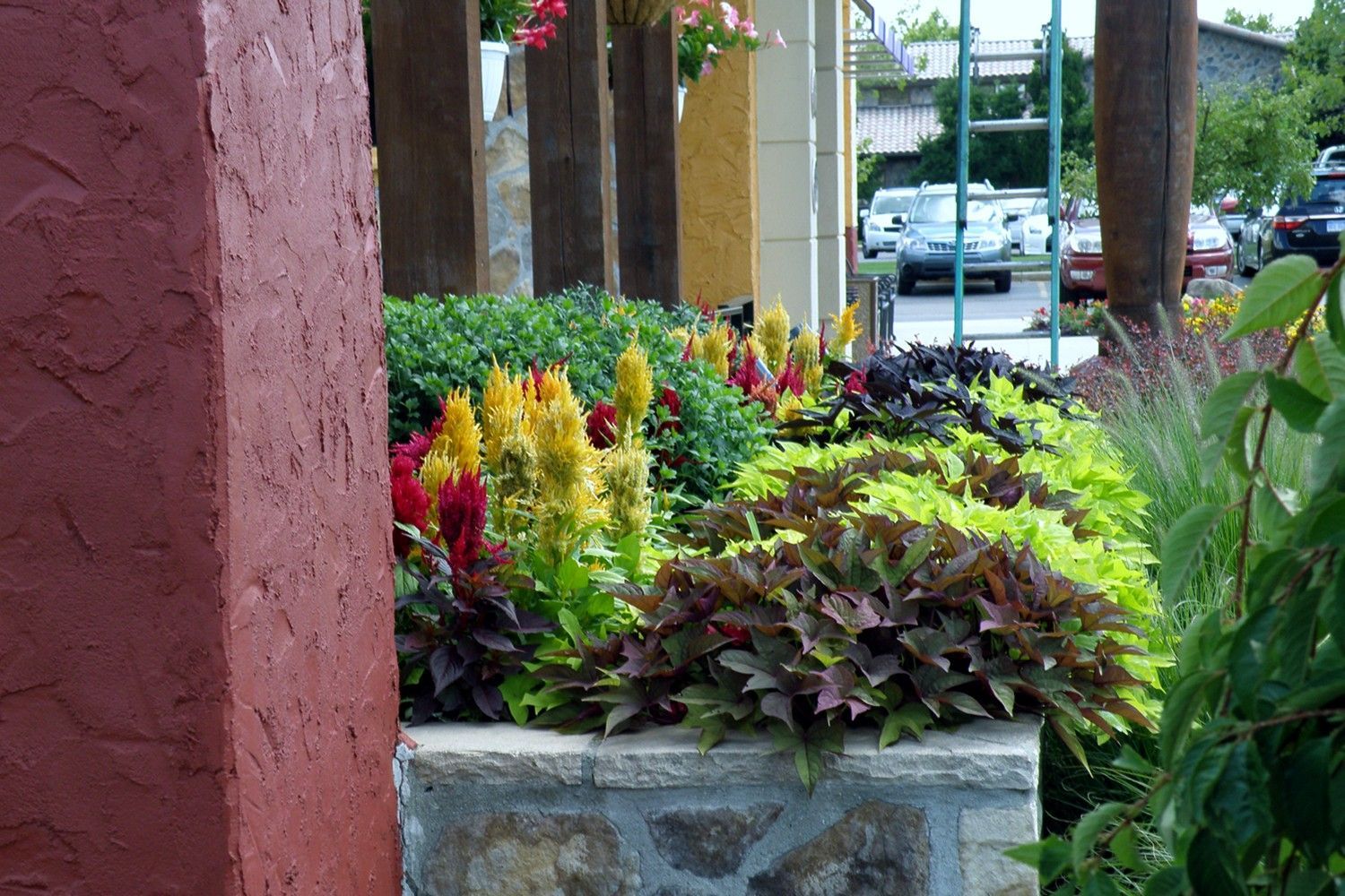 A stone planter filled with flowers and plants in front of a building