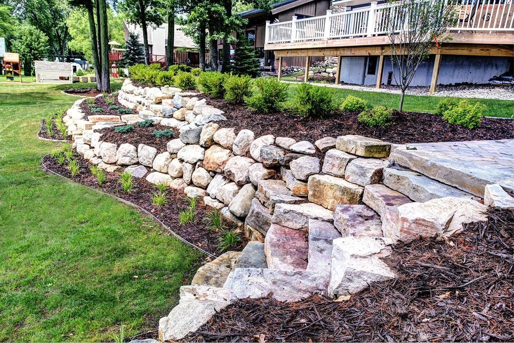 There is a large rock wall in the backyard of a house.