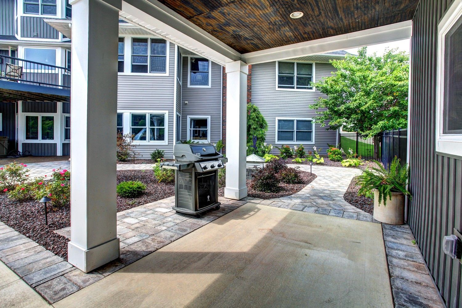 A covered patio with a grill in the middle of it.