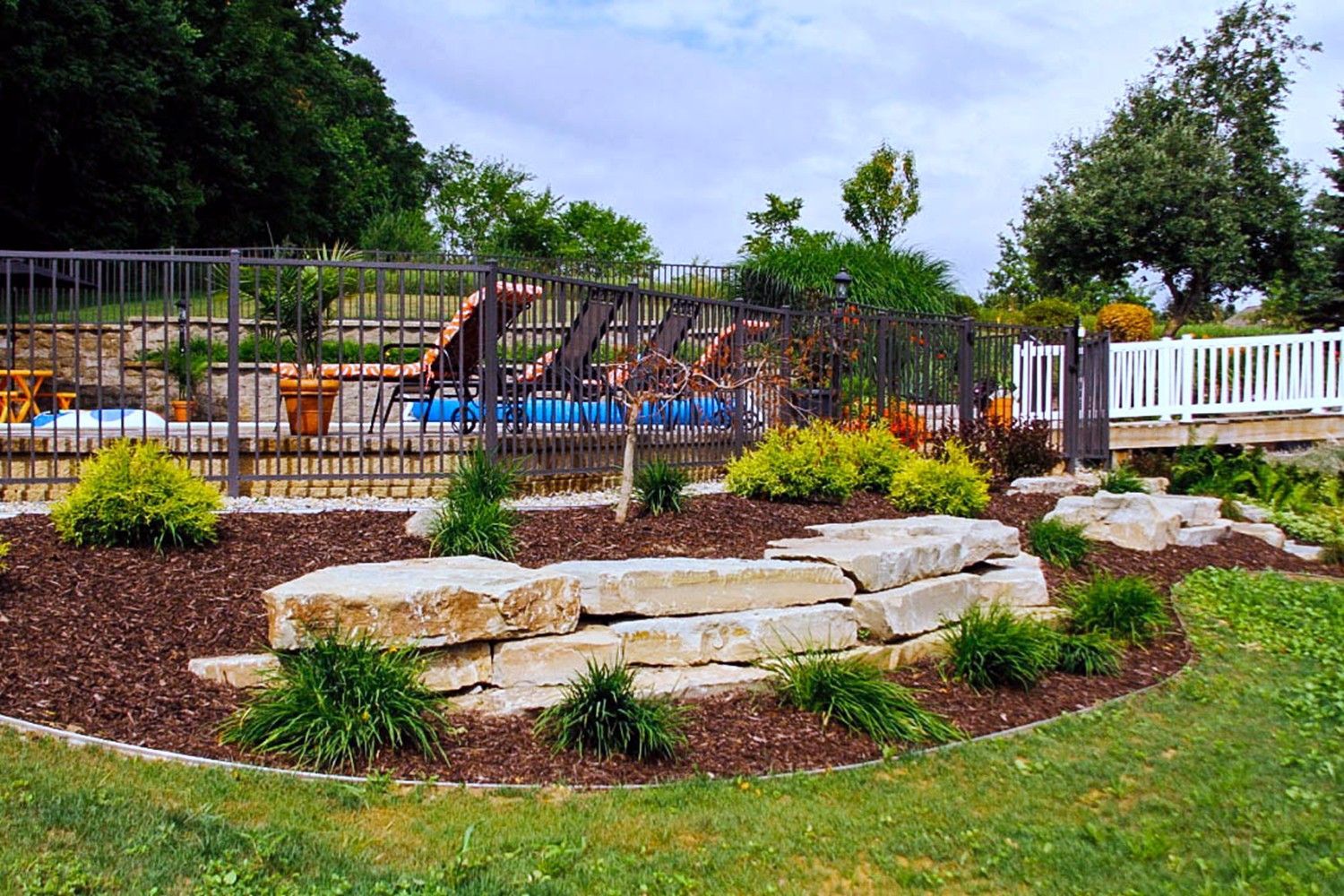 There is a large rock wall in the middle of the yard.