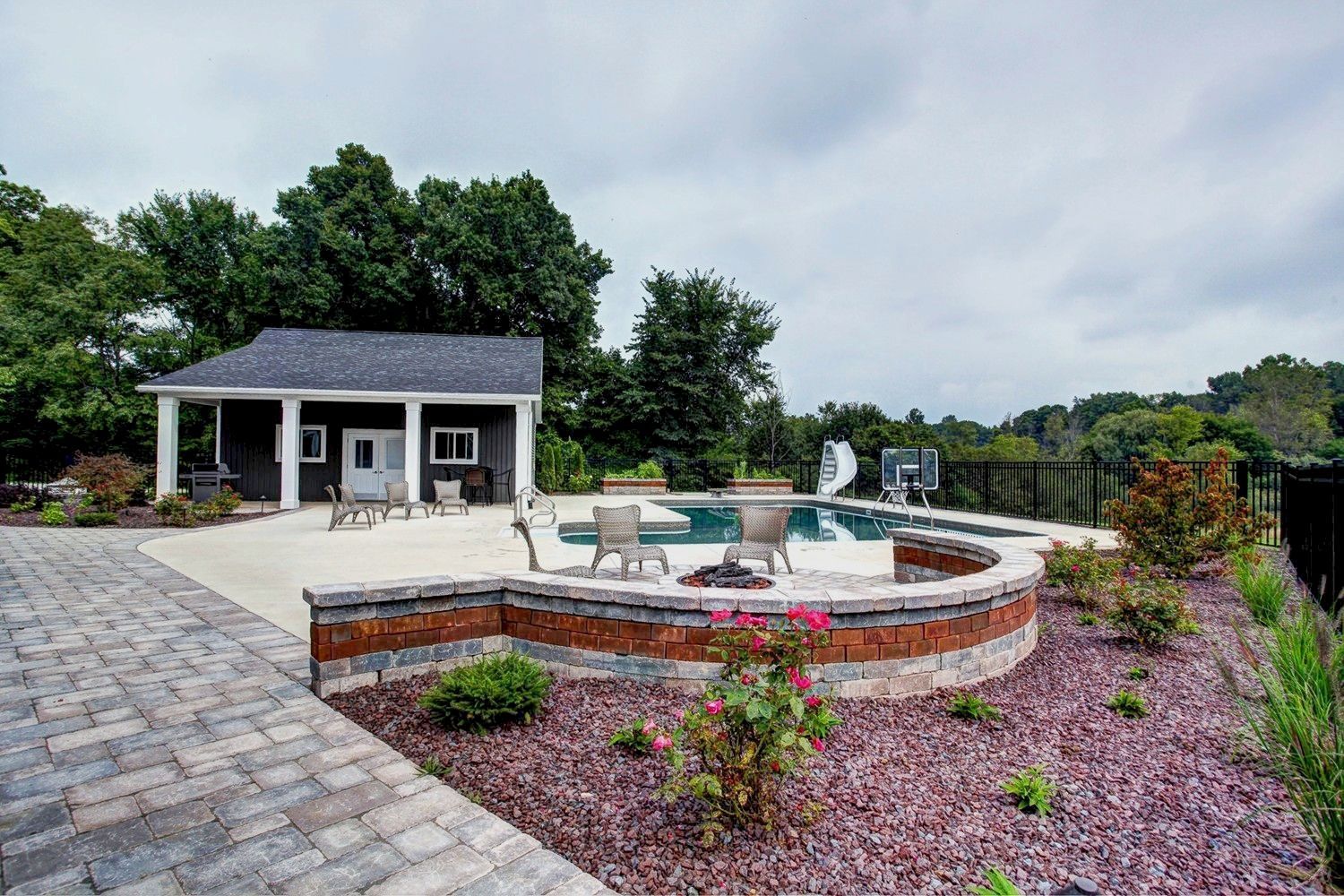 There is a swimming pool in the backyard with a fire pit