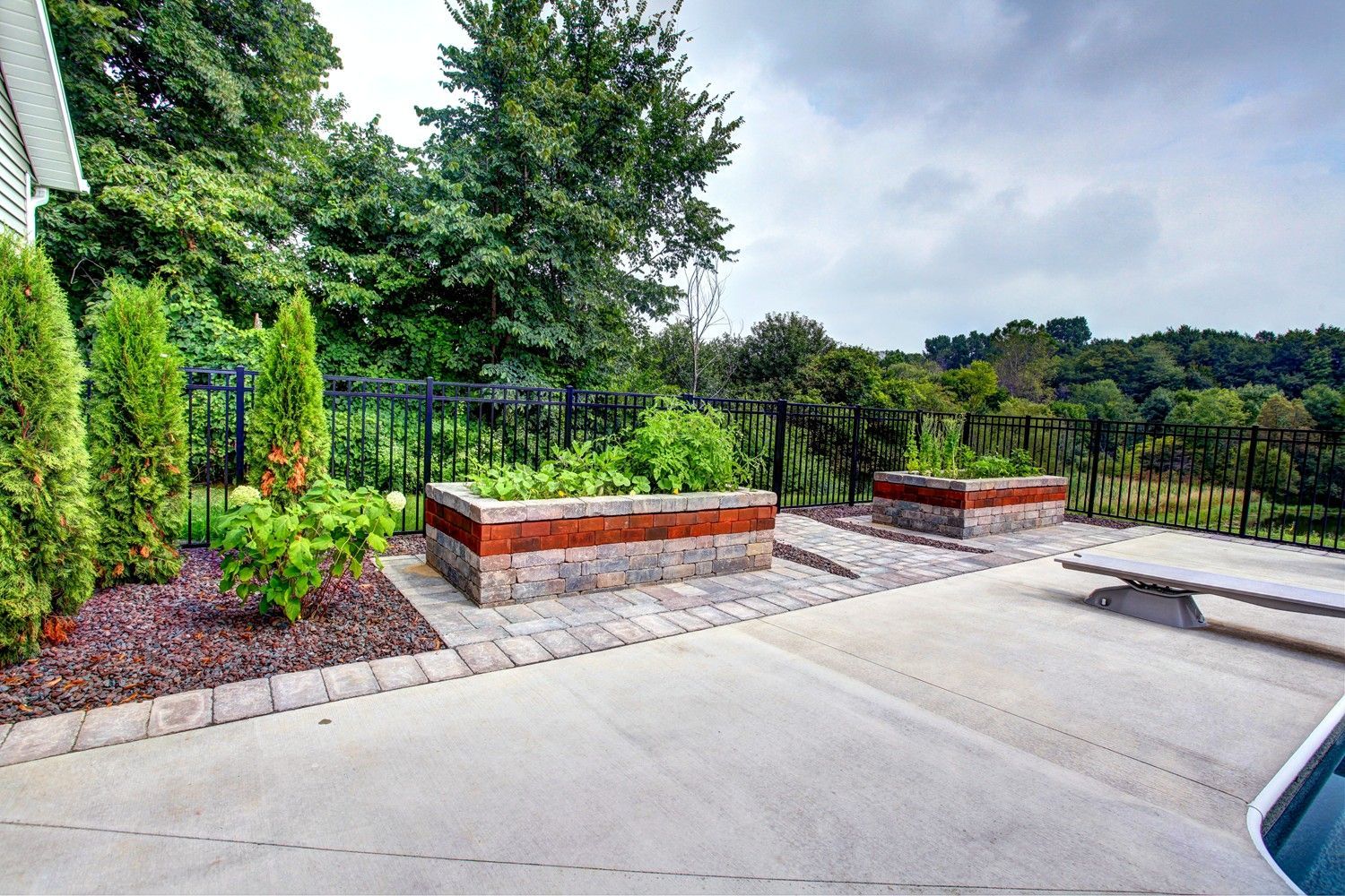 A patio with a fence and trees in the background