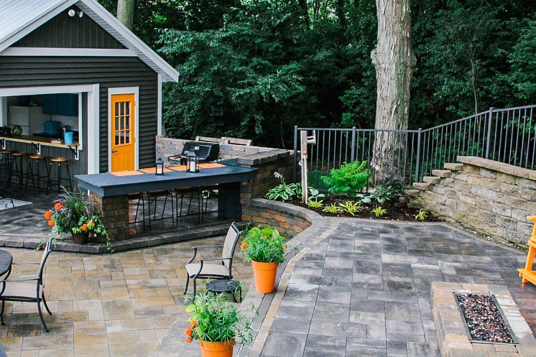 A patio with chairs and potted plants in front of a shed