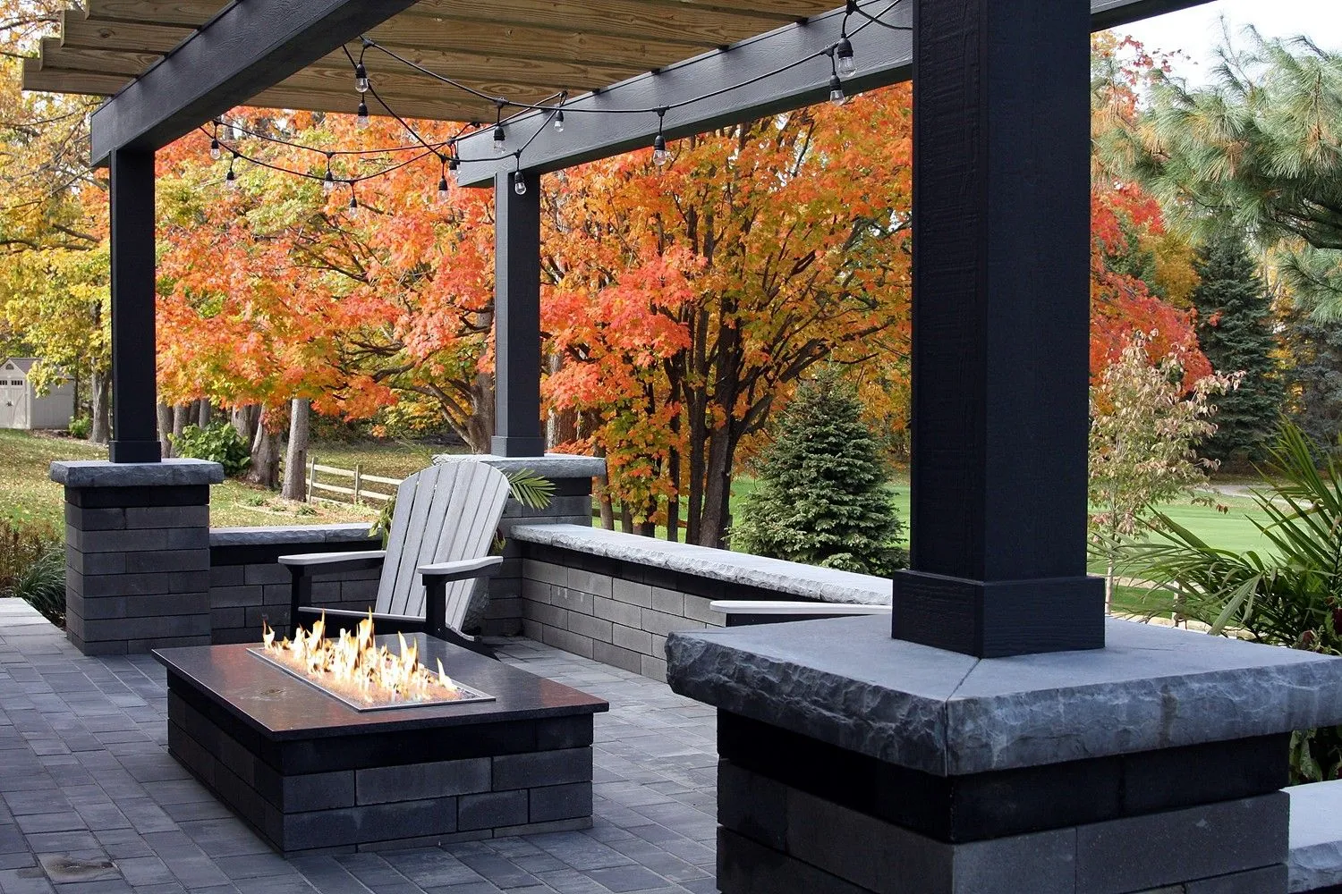A patio with a fire pit and chairs under a pergola
