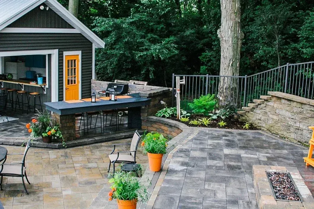 A patio with a fire pit and a shed in the background