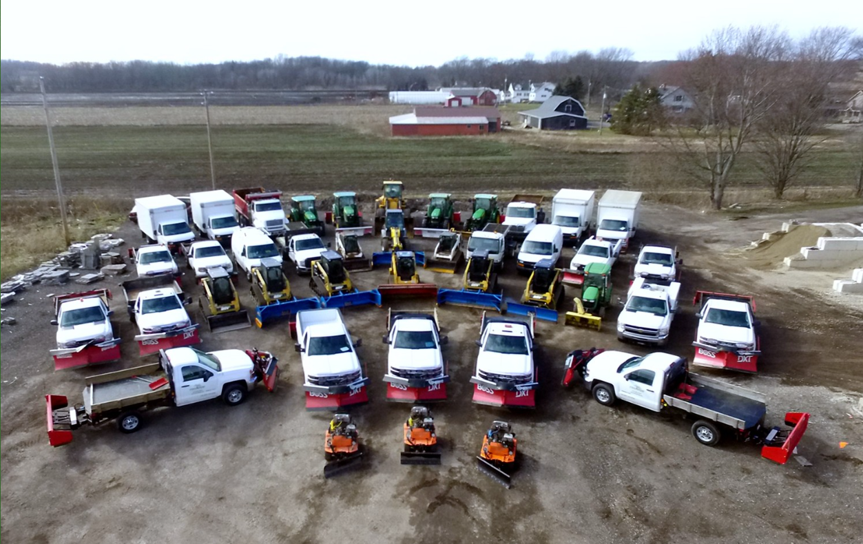 A large group of trucks and tractors are lined up in a parking lot