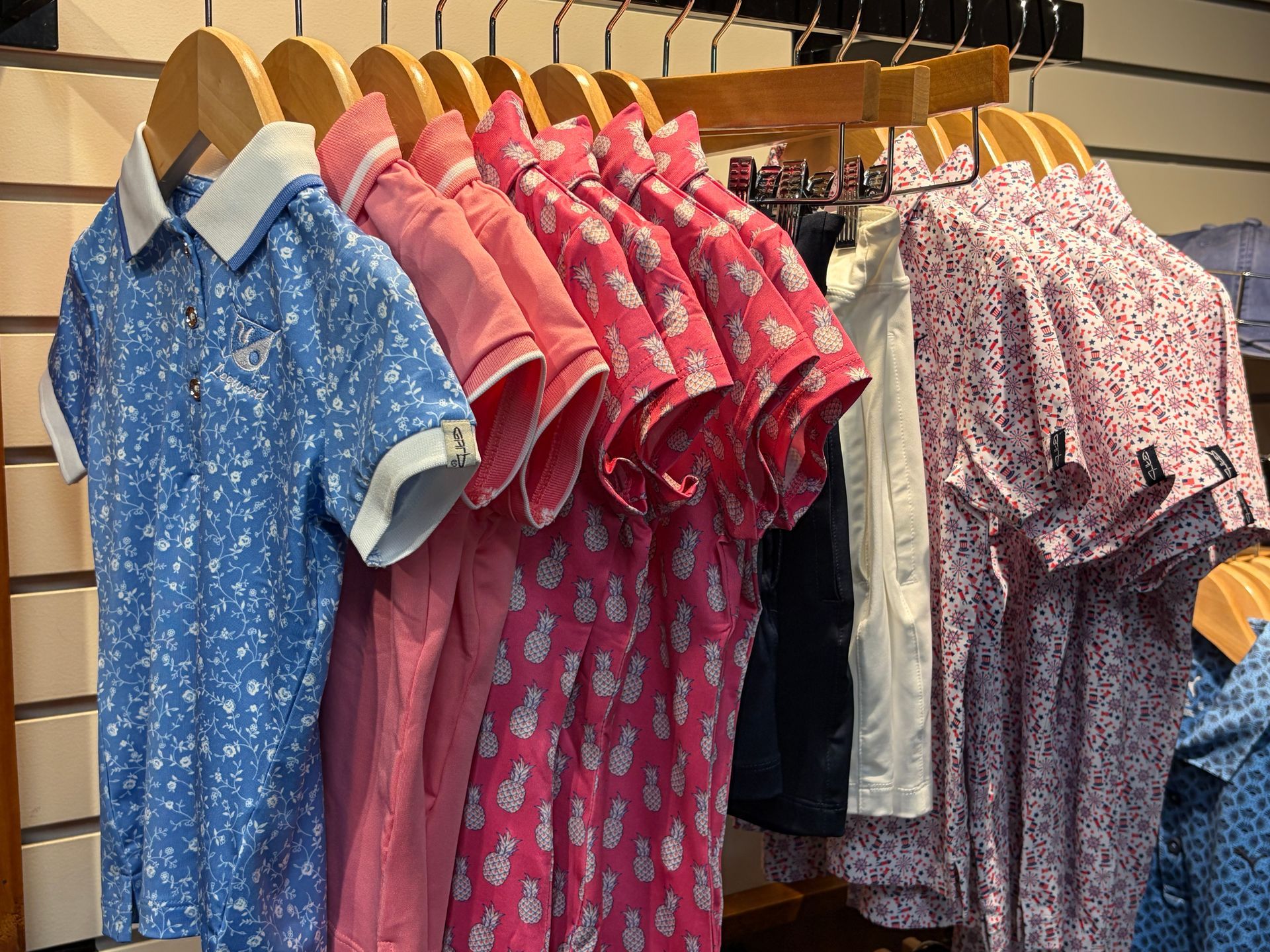 Colorful patterned shirts on wooden hangers displayed on a clothing rack in a shop