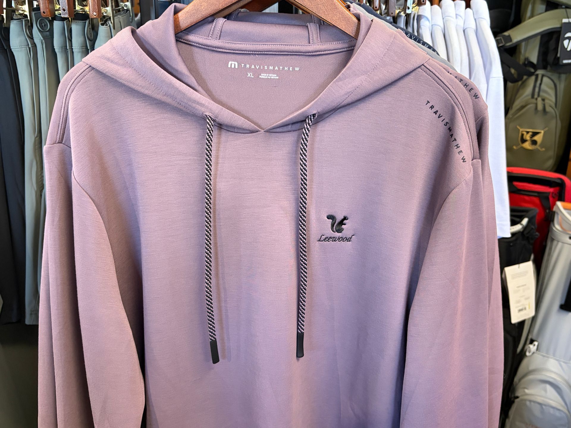 Lavender hoodie with drawstrings hanging on a clothing rack in a store
