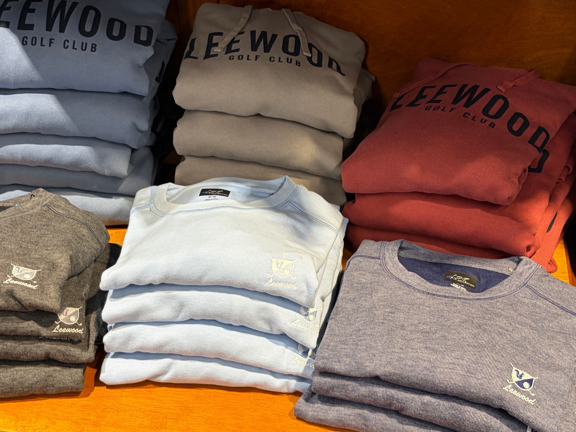 Stacks of folded sweaters in gray, white, beige, red, and blue on store shelves