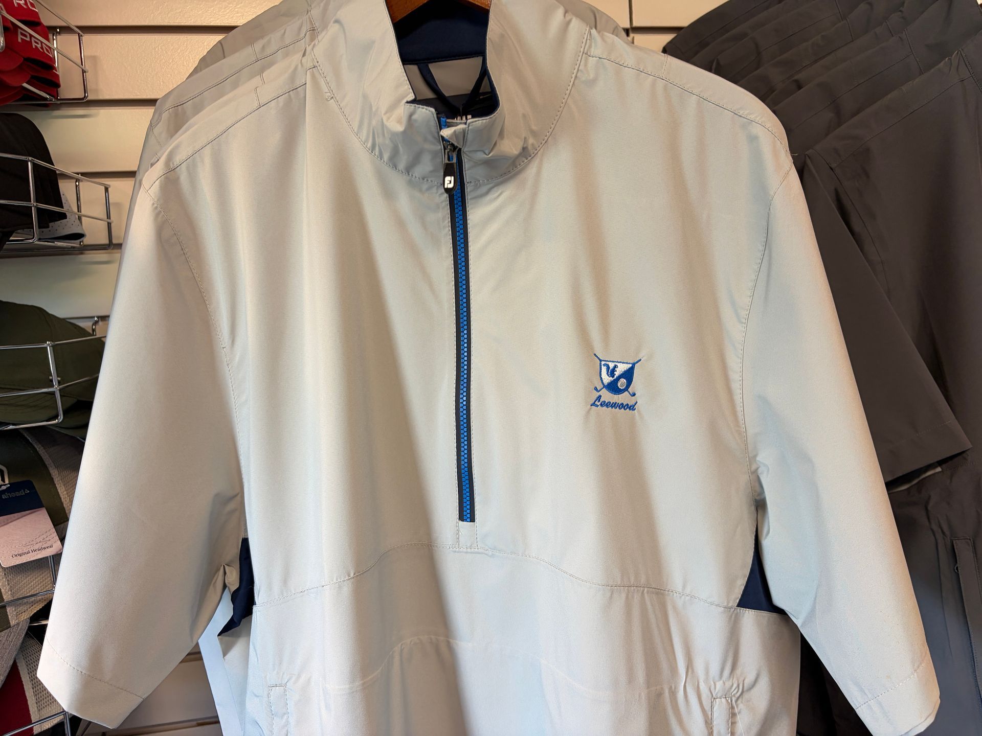 Light gray zip-up jacket with blue trim hanging on a store display rack.