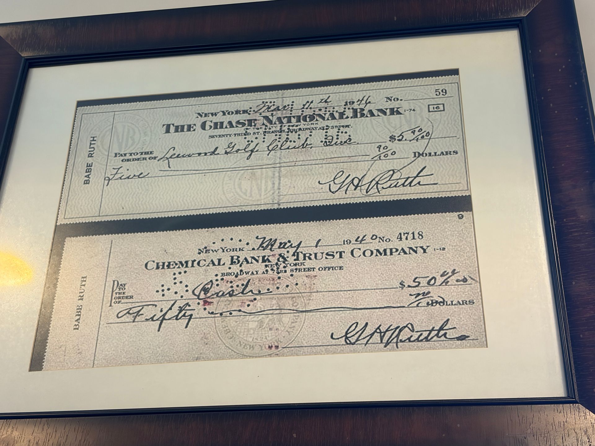 Framed display of two vintage bank checks on a white background