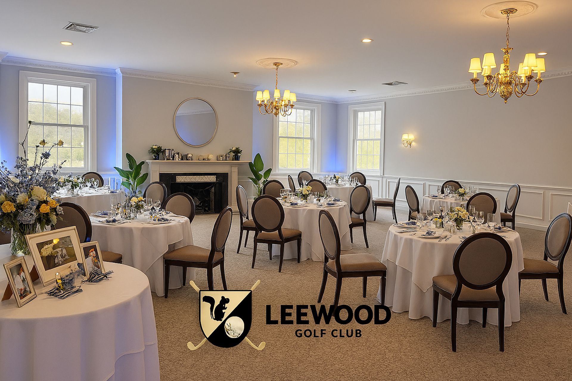 A ballroom at Leewood Golf Club, set for an event, with round tables, chairs, and chandeliers.