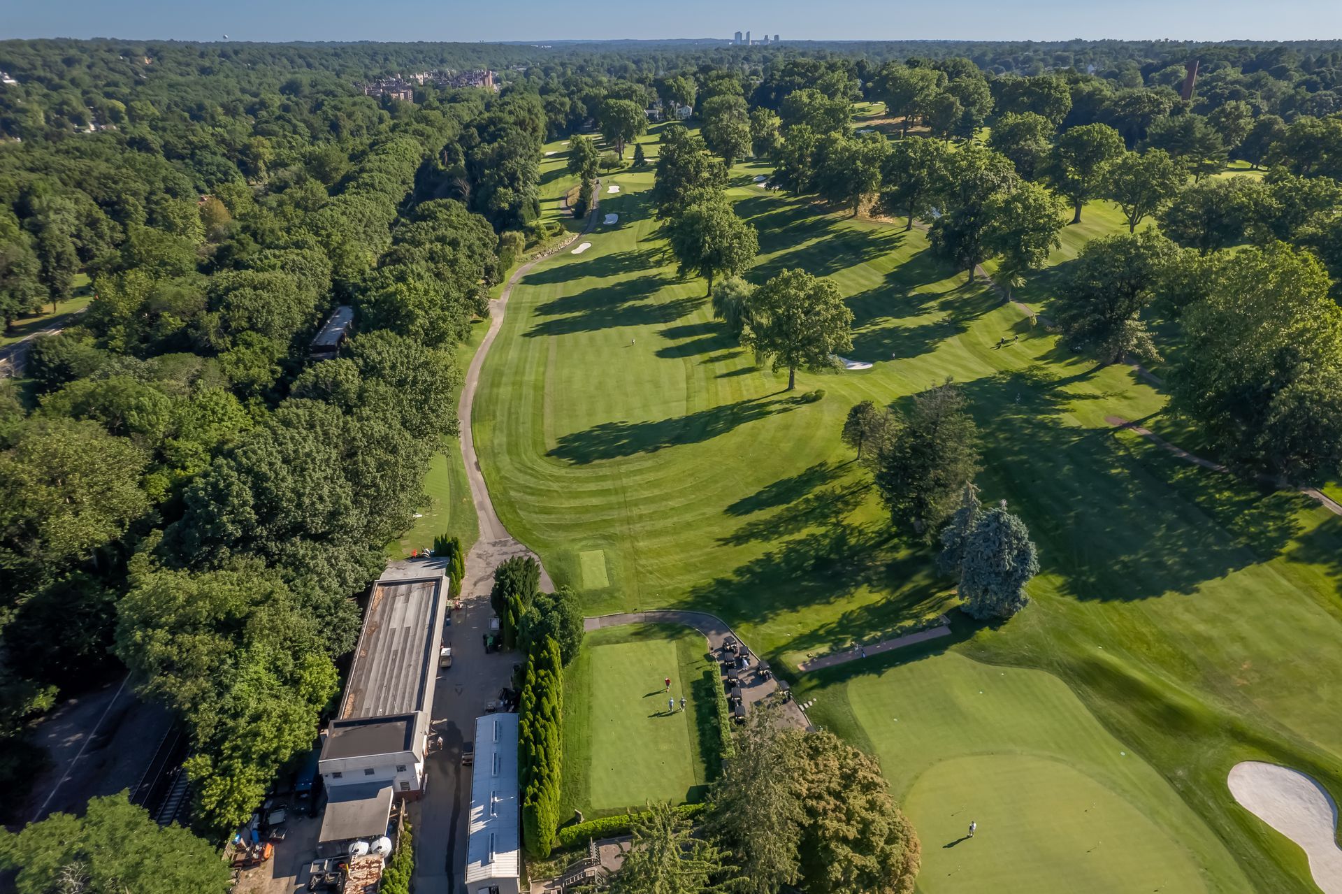 Aerial view of a green golf course surrounded by trees and a building.