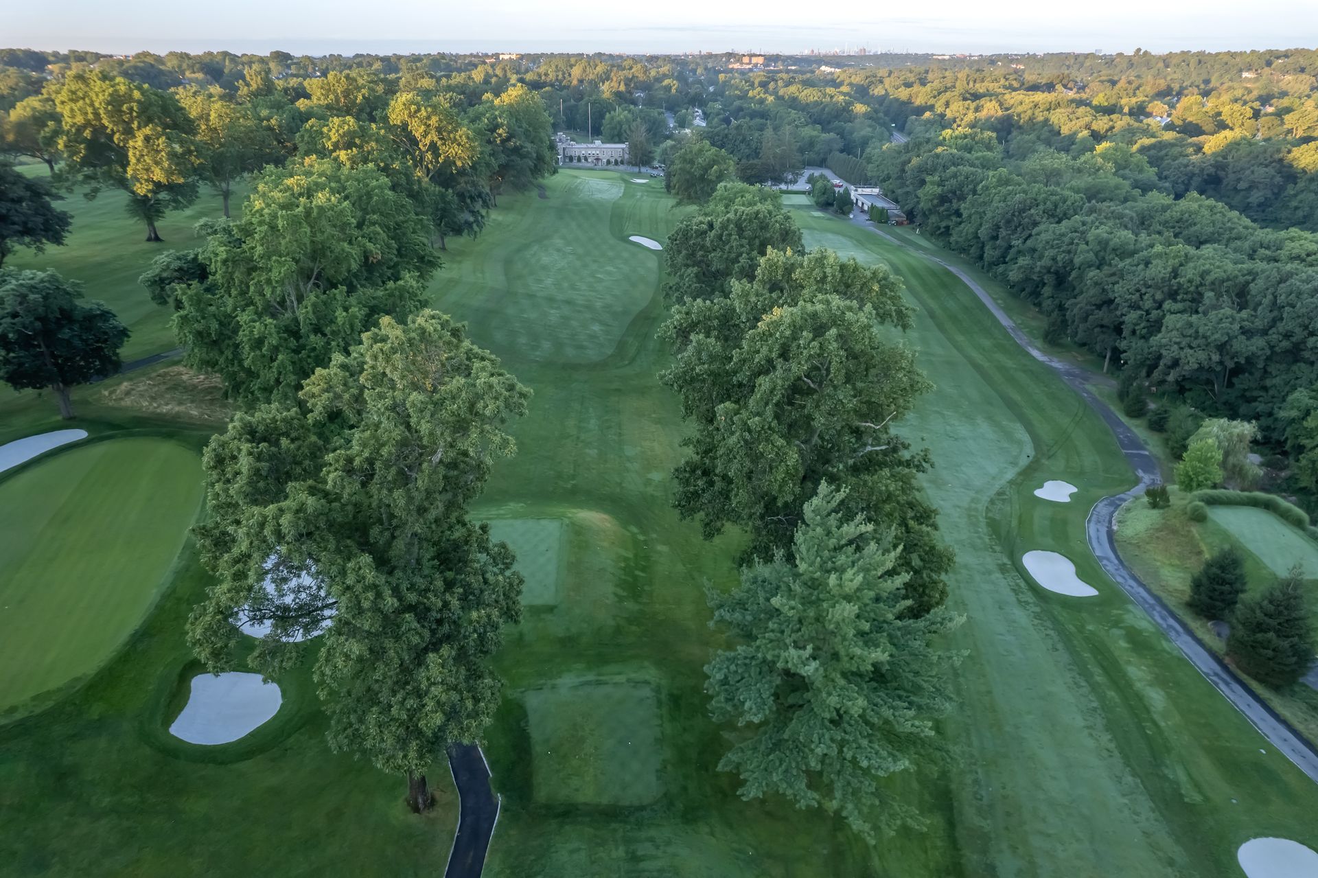 Aerial view of a green golf course with trees lining the fairway and sand traps.