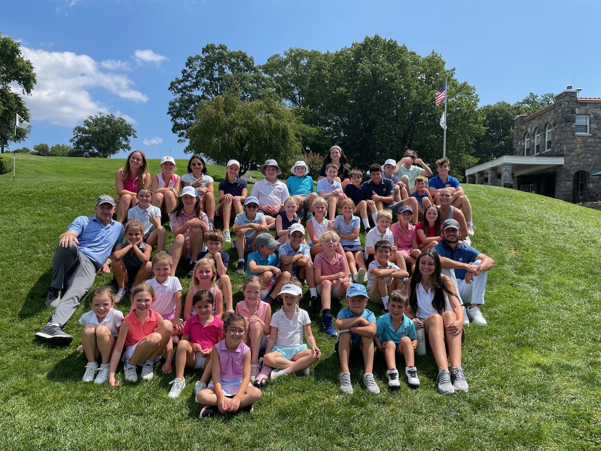 Two boys playing tennis on a court with a net; other children in background.