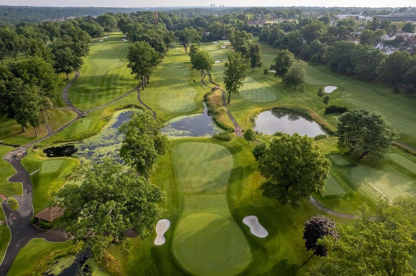 Aerial view of a green golf course with ponds, trees, and fairways.