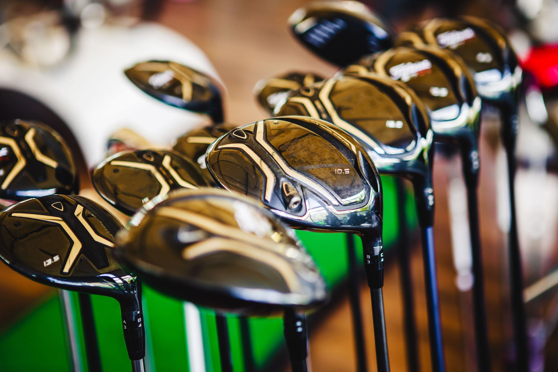 Close-up of golf club heads, black and shiny, lined up with focus on front club.